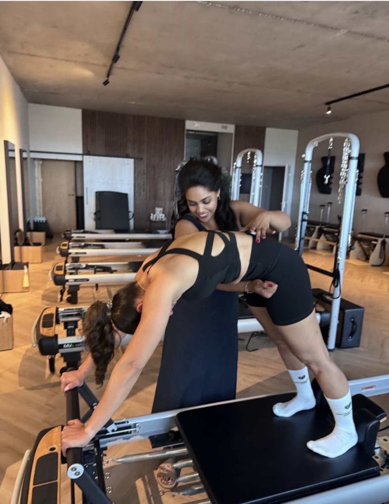 Jocelyn guiding a client hands-on through a stretch on the reformer