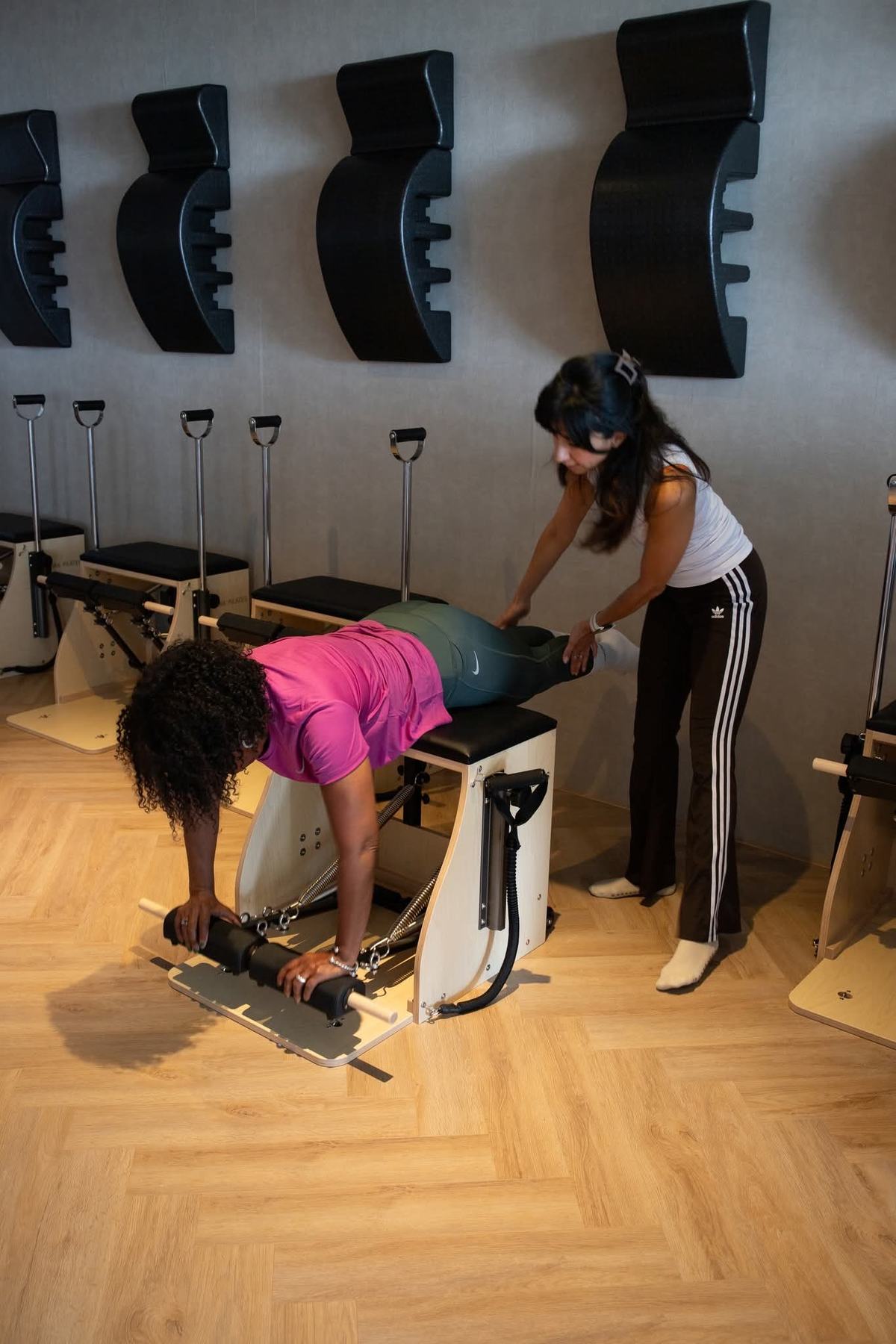 A teacher guiding a client hands-on on the Pilates chair